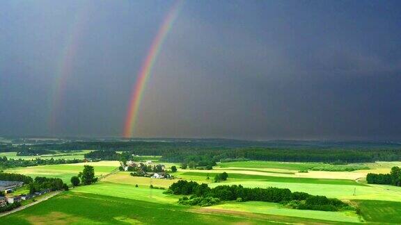 暴风雨后绿色田野上空的彩虹鸟瞰图