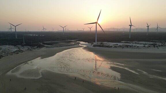 日落时海滩上风力发电厂的鸟瞰图