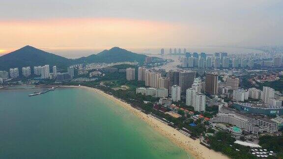 日落时分三亚著名的大东海城市景观拥挤的海滩湾航拍全景4k海南中国