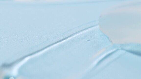 在蓝色背景上涂抹透明的化妆品液体人体血清凝胶芦荟透明质酸样品特写
