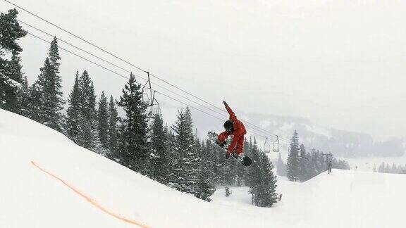 完整的冬季装备滑雪板完成一个“前侧720静音”的技巧与森林和滑雪跳跃在一个下雪的阴天科罗拉多州博尔德附近的埃尔多拉滑雪度假村的背景