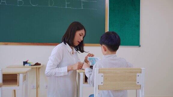 亚洲美女女老师在教室里教小男生在幼儿园有魅力的女教师在课堂上给孩子们讲解和教育课程