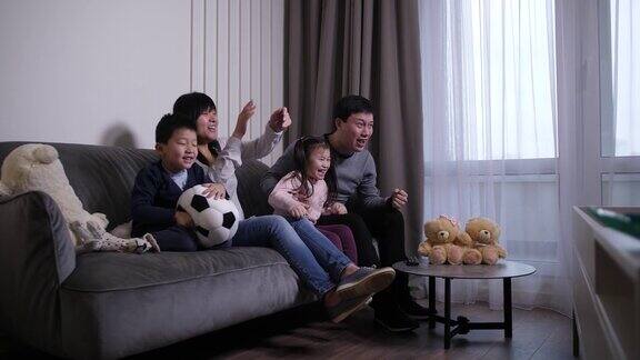 欢乐的中国家庭在电视上观看足球比赛