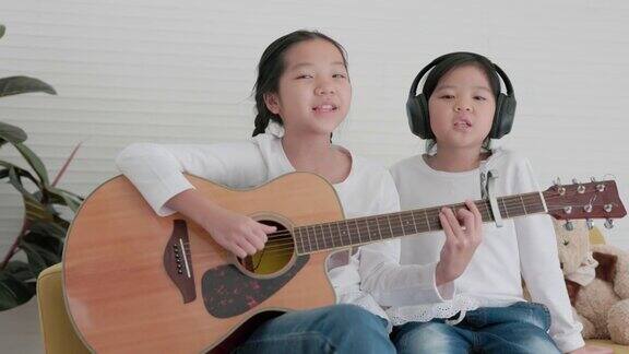 两姐妹在客厅里玩得很开心在舒适的家中你们可以一起弹吉他和唱歌