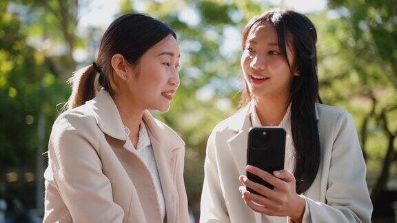 年轻的成年女性亚洲商人在办公室外用手机向客户展示投资财务报告