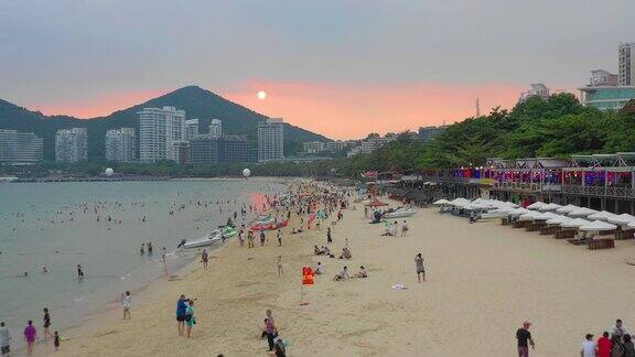 日落时分三亚著名的大东海拥挤的海滩航拍全景4k海南中国