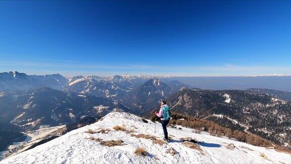奥地利卡林西亚卡拉万克斯雪峰上背着背包的女子到达弗莱堡的峰顶欣赏风景泽尔Pfarre朱利安阿尔卑斯山阳光灿烂的冬日自由