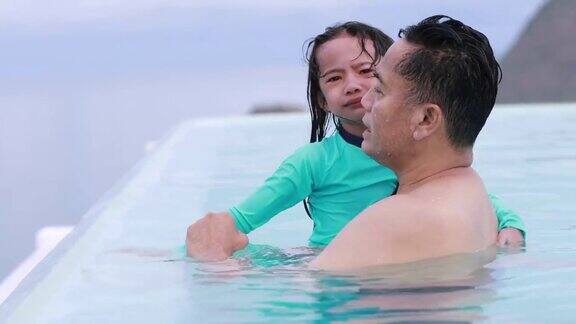 在一个阳光明媚的日子里父亲和女儿在游泳池里玩耍