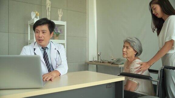 一名男性医生报告说治疗结果有所改善告知医院里坐轮椅的老年女性患者