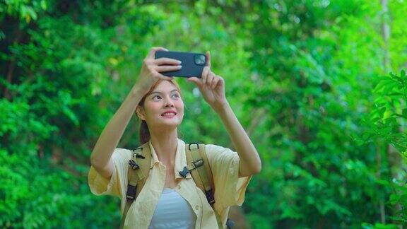 年轻的亚洲旅行者在森林里散步时用手机拍照