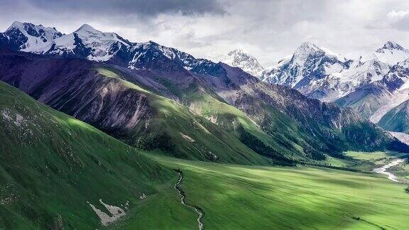 航拍新疆的绿色草原和雪山自然景观