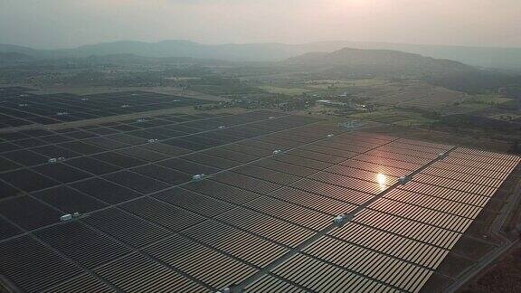 鸟瞰图飞过太阳能农场站在日落的观点:能源概念