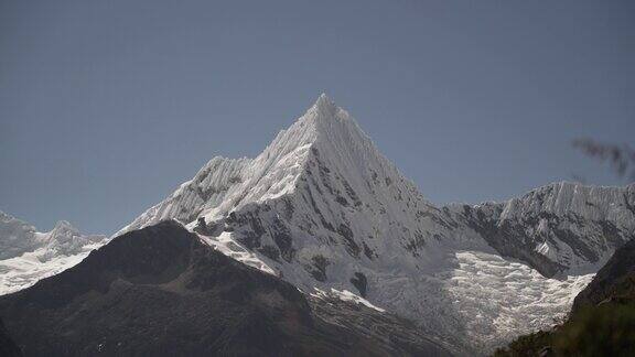 在秘鲁华斯卡兰的白科迪勒拉安第斯山脉的高山上拉古纳帕隆泻湖的一座金字塔形山的冰川被冰雪覆盖阳光明媚的日子里山峰被白雪覆盖