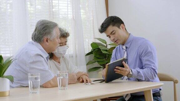 健康医生上门拜访一对老年夫妇医生检查检查一位祖母在平板上描述病情