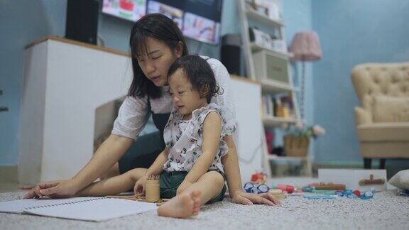 亚洲华人母亲在客厅教女婴画画