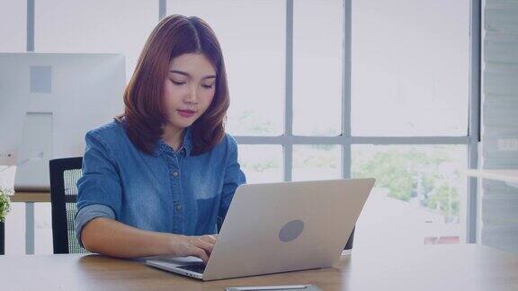 年轻的亚洲商务女性在办公室用笔记本电脑工作