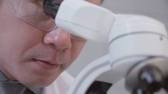 亚洲科学家在实验室通过显微镜进行研究