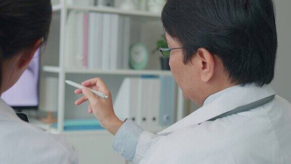 医疗队亚洲男、女医生在医院电脑上检查病人的x线图像讨论结果医疗保健