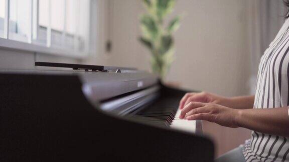 年轻女子在家里练习钢琴成年人音乐家的手喜欢玩数字钢琴自学乐器