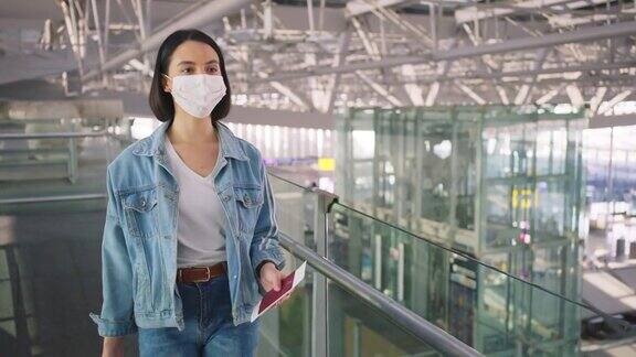 新冠肺炎疫情期间佩戴口罩的女乘客在机场航站楼走向登机口以防止感染新冠肺炎飞机运输的新常态生活理念