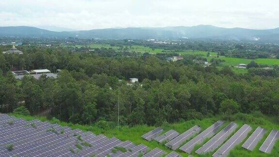 鸟瞰图的太阳能电池板光伏在农村地区无人机飞越绿色田野中的太阳能电站进行发电