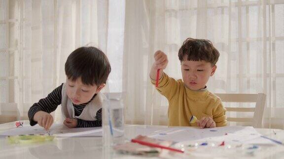 两个小男孩在窗前画画