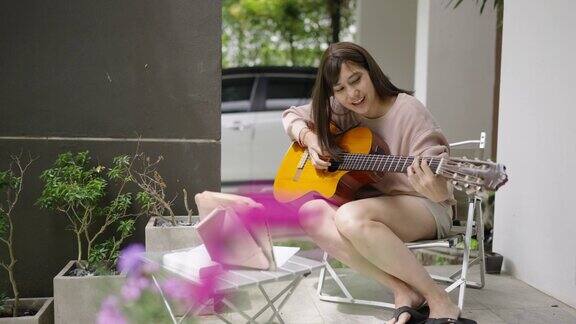 一位妇女坐在屋外正在网上学习如何弹吉他