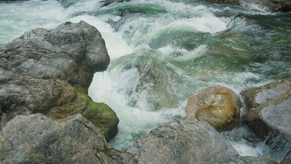 强大的蓝色水流湍急地流过岩石激流激流的白水山河清澈的冰川急流特写