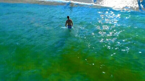 无人机拍摄到一个漂亮的年轻人从海水中走出来