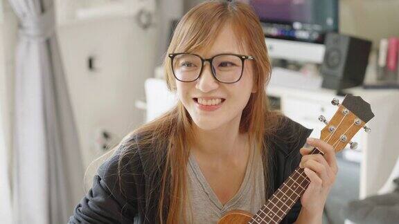 一名亚洲女子喜欢和朋友在网上玩尤克里里琴