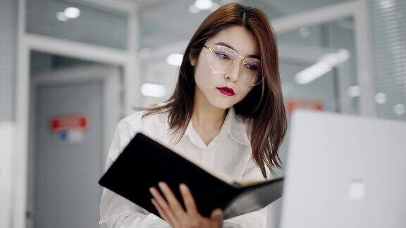 亚裔中国美女经理在办公室用笔记本电脑打字工作