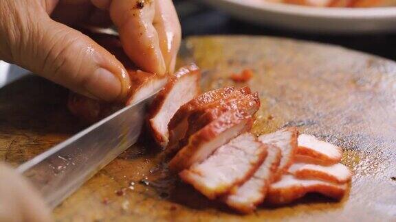 有人用刀切红烤猪肉准备制作中餐菜单煮熟的肉面条