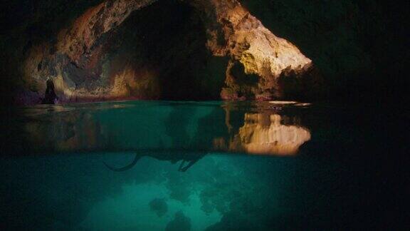 自由潜水者在洞穴中与飞行蝙蝠在水下游泳