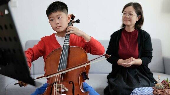 小男孩在家跟老师练习大提琴