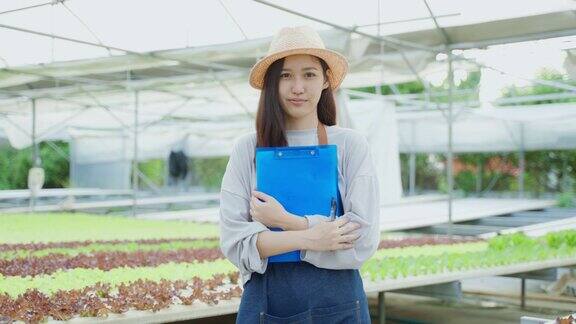 一对亚洲农民夫妇在蔬菜水培农场幸福地工作有吸引力的年轻男子和妇女农学家看和检查绿色橡树的质量在温室农业经营理念