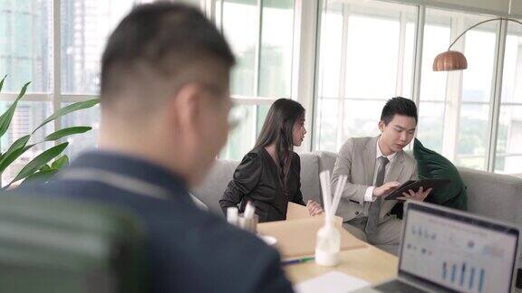 一群在办公室工作的亚洲华人白领同事正在讨论