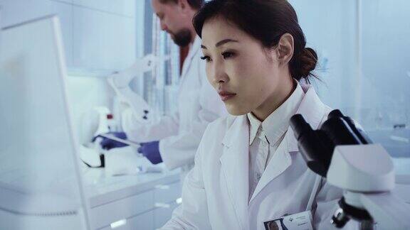 实验室小组处理病原体样本亚洲女医生使用显微镜