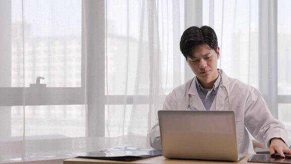 年轻的亚洲男性医生检查他们的情况在办公室