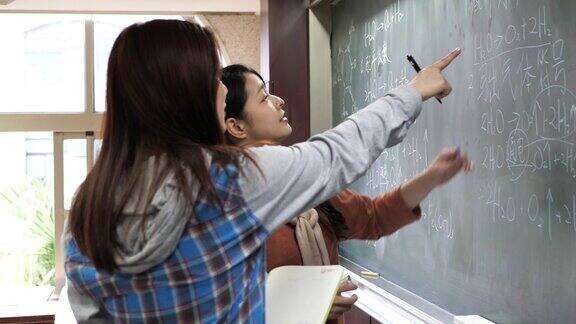 亚洲学生在教室的黑板上写字解决复杂的任务
