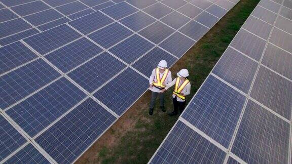 技术工程师在阳光下观察太阳能电池在太阳能发电厂检查太阳能电池板