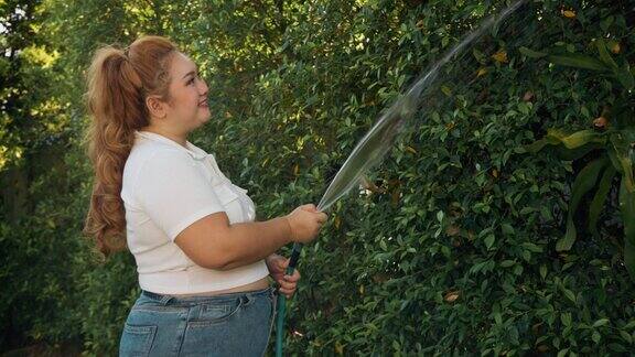 早上一位超重的妇女在家里给植物浇水