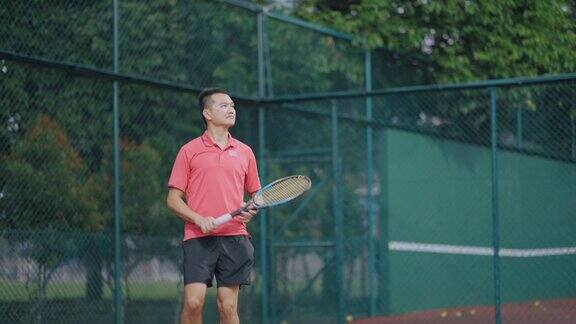 周末晚上亚洲华人男子网球运动员在硬地场上练习