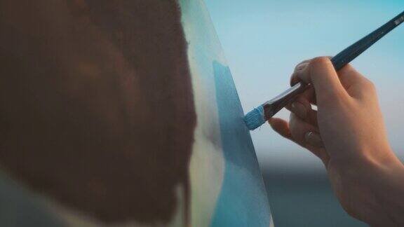 靠近女人的手用画笔在画布上绘画创造性的女艺术家