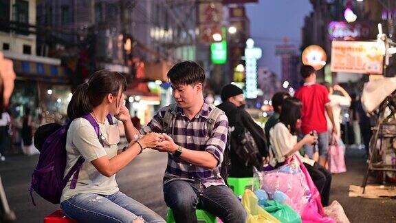 4K亚洲夫妇在曼谷Yaowarat路与人群在街上吃食物