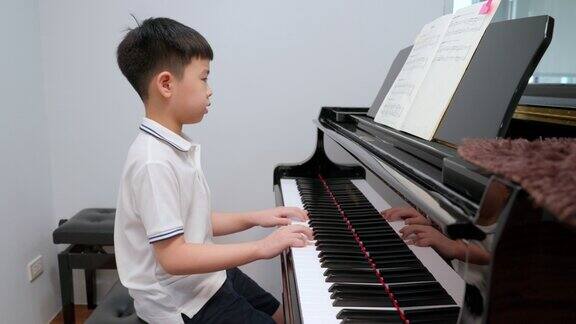 亚洲男孩穿着衬衫在学校教室里弹钢琴考试要上一级教育、技能、学习理念音乐家钢琴练习网络考试新常态
