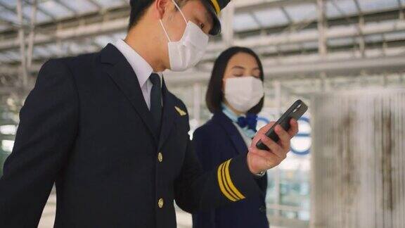 新型冠状病毒感染症(COVID-19病毒)流行期间飞行员和空姐戴着口罩在机场候机楼走向飞机航空运输概念中的新常态生活方式