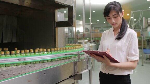 在草药保健饮料制造行业检查产品质量的年轻女性工人饮用水和饮料的生产