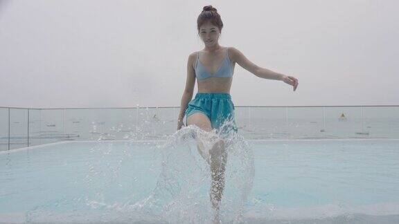 美丽的年轻亚洲女子享受和放松在一个豪华酒店的室外游泳池
