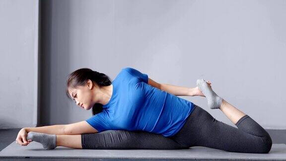 全镜头体操亚洲年轻女子使伸展在垫子上在家里或瑜伽工作室