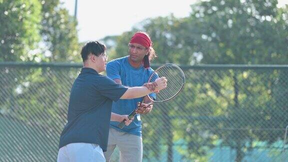 亚洲华人唐氏综合症男子在周末早上向教练学习打网球